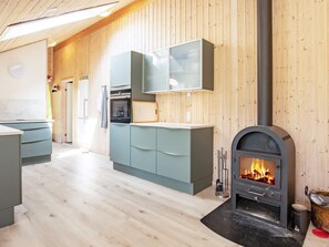 Een moderne keuken met houten lambrisering, een inbouwfornuis en een eethoek met een bank.