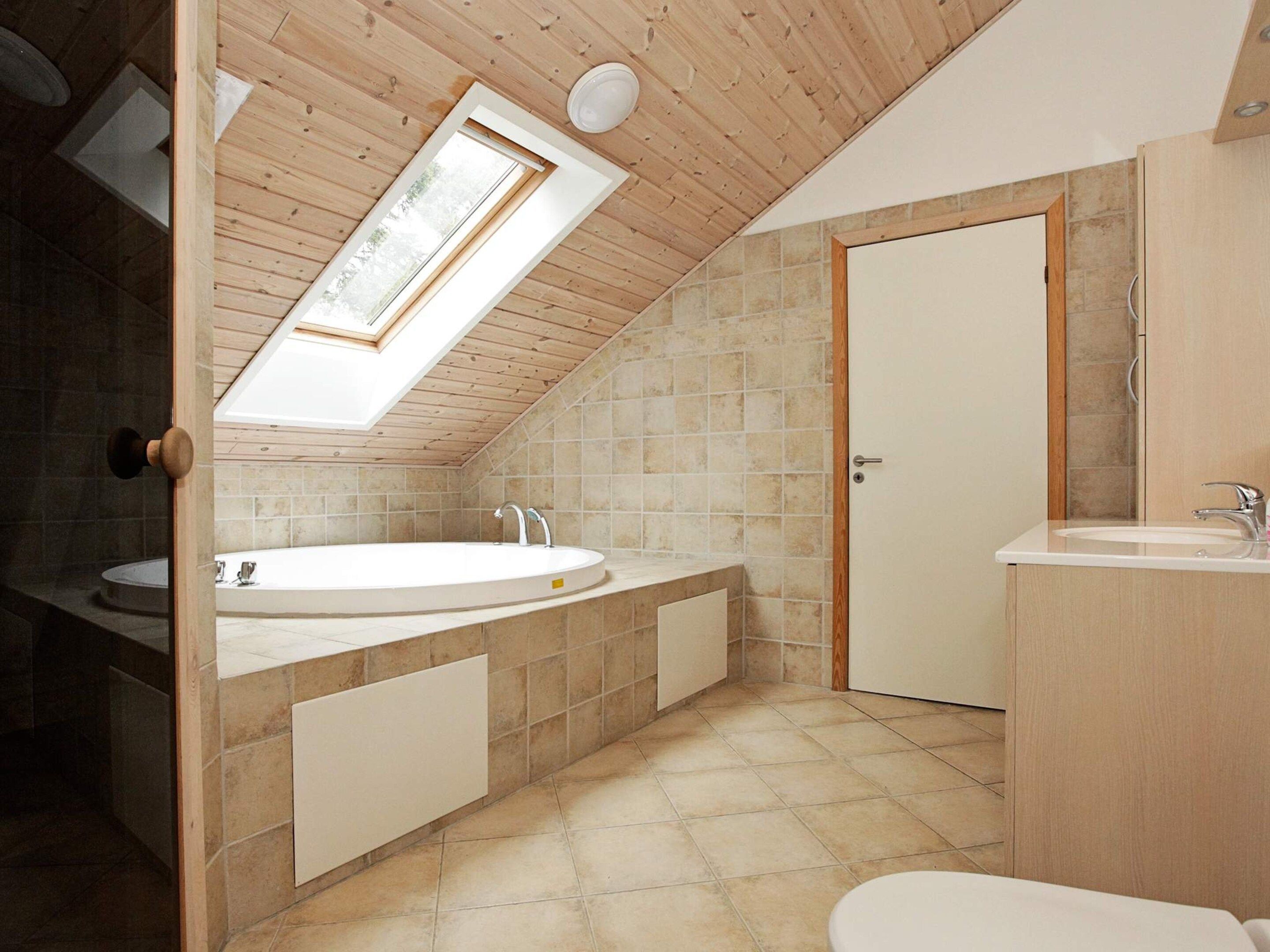 A modern bathroom with a skylight, a freestanding bathtub, and a separate sink area.