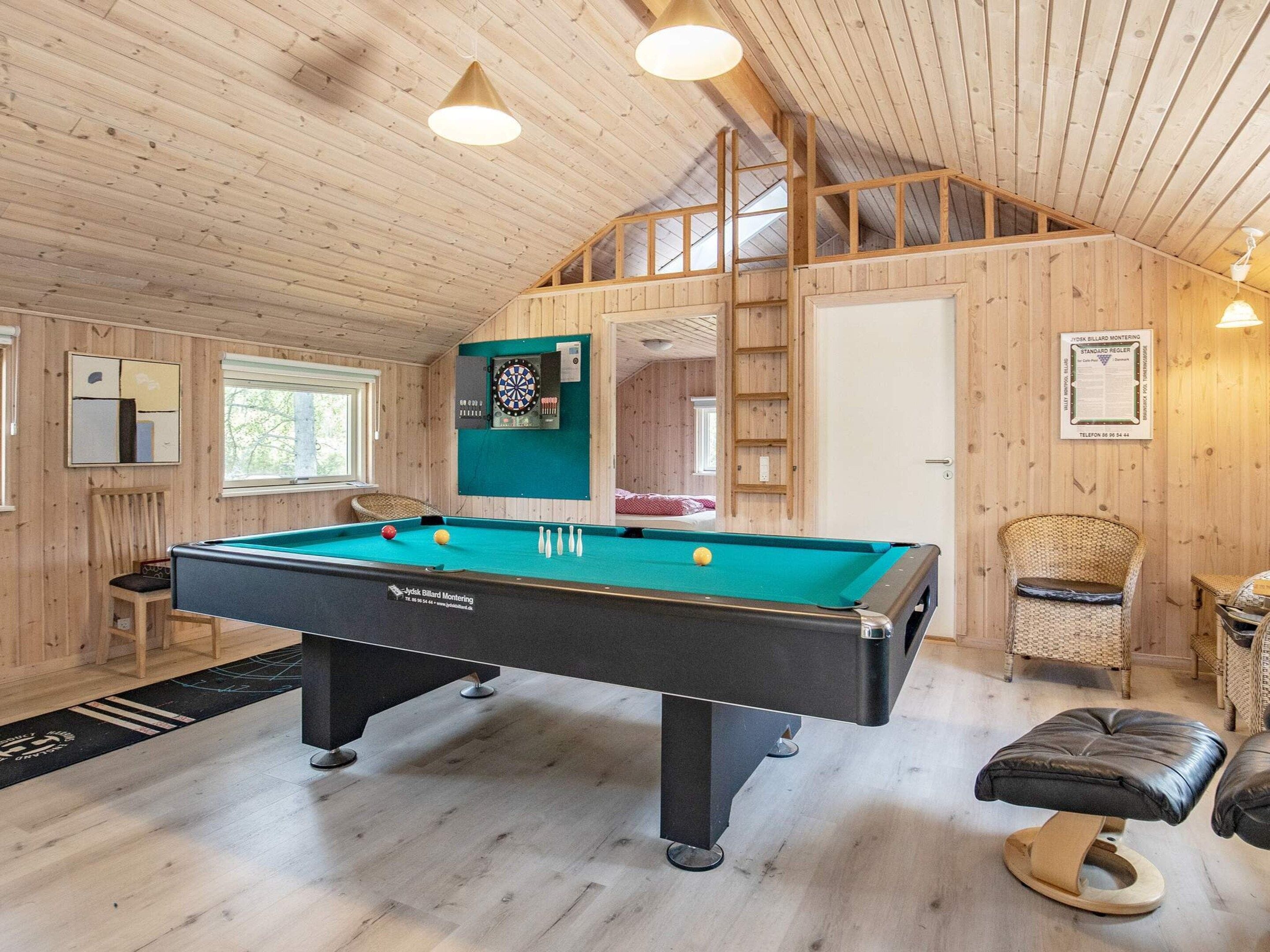 A pool table in a room with wooden walls and a sloped ceiling.