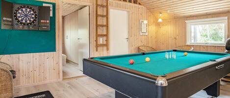 A pool table in a room with wooden walls and a loft area.