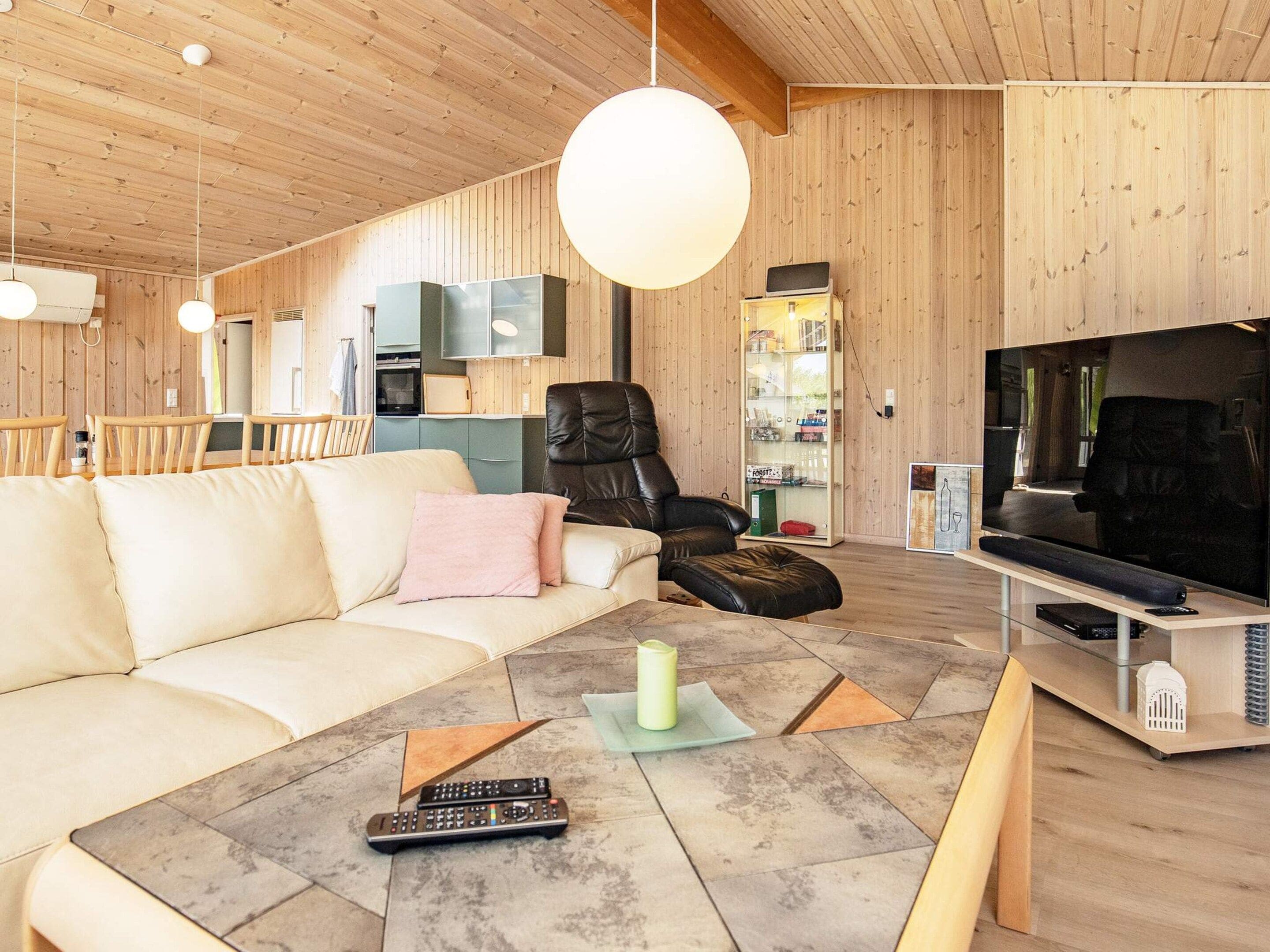 En moderne stue med sofa, læderlænestol, fjernsyn og pejs.