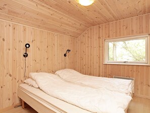 A room with wooden walls and a single bed with white bedding.