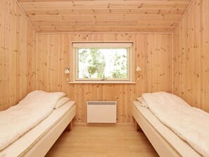 Een kamer met twee bedden, een raam met uitzicht op bomen en een wandradiator.