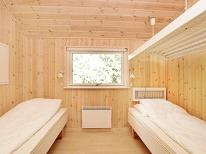 Una habitación con dos camas, una ventana con vistas a zonas verdes, un radiador y una lámpara en el techo.