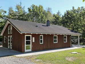 A small wooden cabin with a peaked roof, a chimney, and a porch.