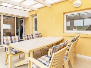 A sunlit patio with a table and chairs, a sliding glass door, and a view of the countryside. - 11 Person Holiday Home in Thisted (Thisted)