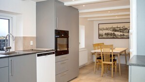 Eine moderne Küche mit Einbauofen, Essbereich mit Tisch und Stühlen sowie ein großes Fenster für natürliches Licht.