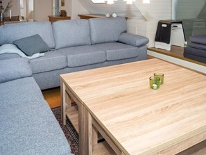 En moderne stue med en grå sofa, et træbord og et lille sofabord med stearinlys.