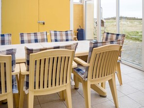 A room with a yellow door, a table with chairs, and a view of a field through a glass door. - 11 Person Holiday Home in Thisted (Thisted)
