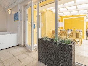 A hotel room with a bathtub, a wicker planter with greenery, and a yellow wall. - 11 Person Holiday Home in Thisted (Thisted)