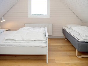 A bedroom with a sloped ceiling, a window, a radiator, and two beds. - 11 Person Holiday Home in Thisted (Thisted)