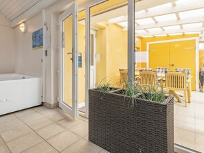 A hotel room with a bathtub, a wicker planter, and a dining area with yellow walls and wooden furniture. - 11 Person Holiday Home in Thisted (Thisted)
