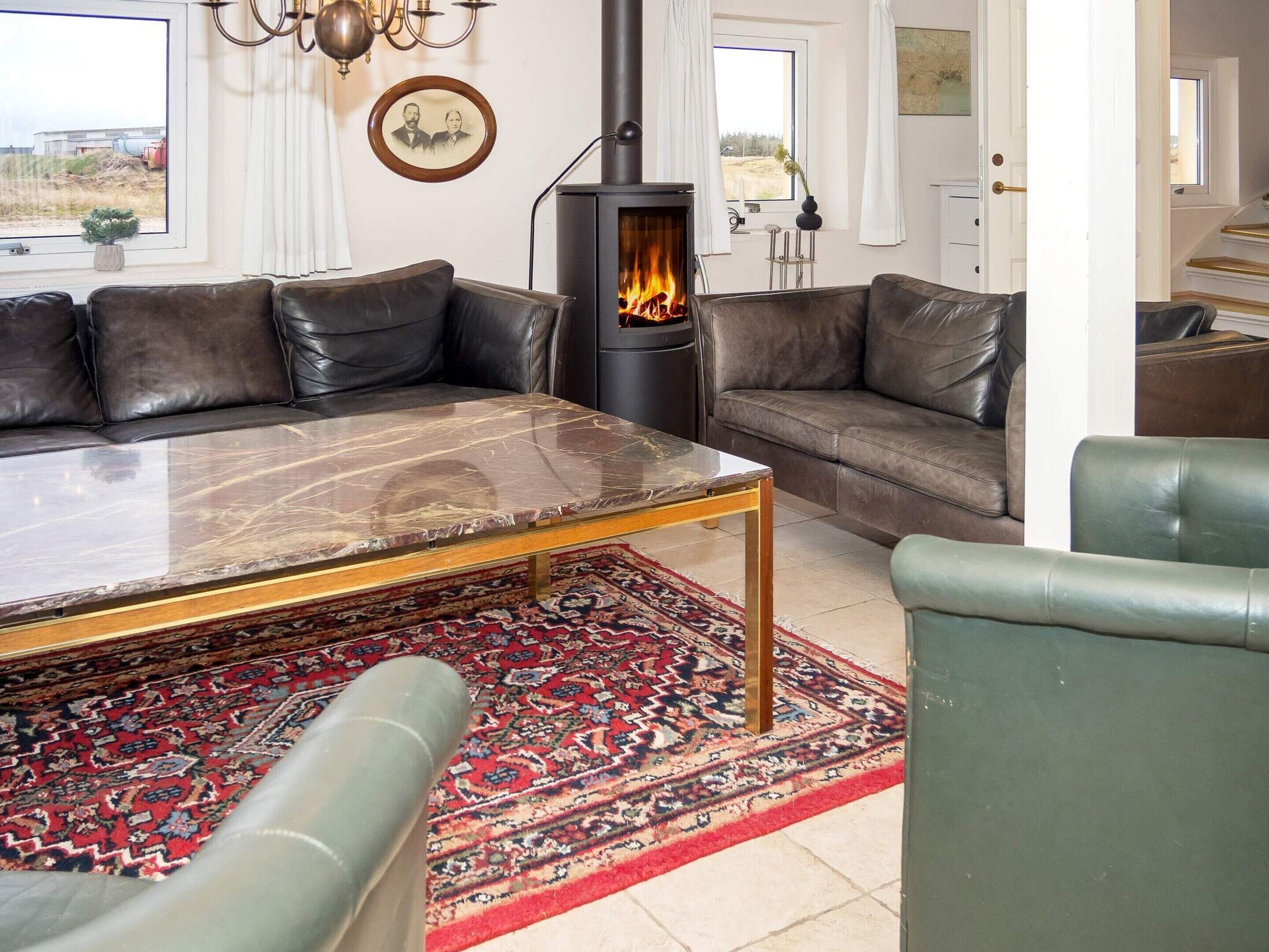 A living room with a sofa, a coffee table, a rug, and a wood-burning stove.