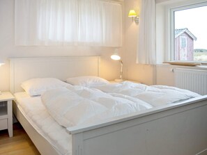 A bed with white bedding, a bedside lamp, and a window with a view of a red building. - 11 Person Holiday Home in Thisted (Thisted)