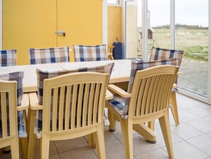 A dining area with a yellow wall, a table with chairs, and a view of the outdoors. - 11 Person Holiday Home in Thisted (Thisted)