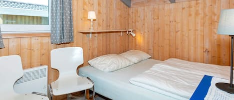 A room with a bed, a chair, a table, and a lamp.