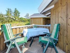Un patio al aire libre con una mesa y dos sillas, rodeado de vallas de madera.