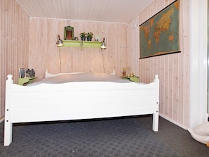 A room with a white bed, wooden walls, a world map, and a shelf with plants and a picture. - Attractive Holiday Home in Hemmet near Sea (Hemmet)