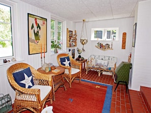 A cozy room with wicker furniture, a red carpet, and a bookshelf. - Attractive Holiday Home in Hemmet near Sea (Hemmet)