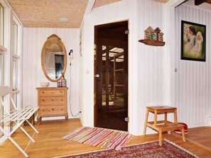 A room with a wooden bench, a dresser with drawers, a mirror, a door leading to a balcony, a small wooden stool, and a colorful rug. - Attractive Holiday Home in Hemmet near Sea (Hemmet)