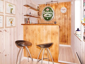 Zona de bar con pared de madera, un reloj y cuadros enmarcados.