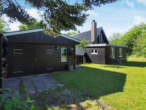 A modern house with a large garage, a well-maintained lawn, and a chimney.