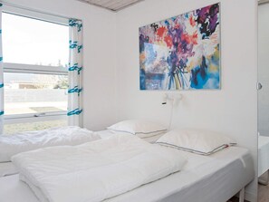 A bedroom with two single beds, a window with curtains, and a colorful abstract painting on the wall. - 4 Star Holiday Home in Ebeltoft (Ebeltoft)