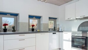 A modern kitchen with white cabinetry, a built-in oven, and a tiled floor. - 4 Star Holiday Home in Ebeltoft (Ebeltoft)