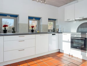 Eine moderne Küche mit weißen Schränken, einem eingebauten Backofen und einem gefliesten Boden.