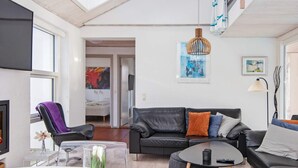 A modern living room with a sofa, coffee table, and a TV. - 4 Star Holiday Home in Ebeltoft (Ebeltoft)