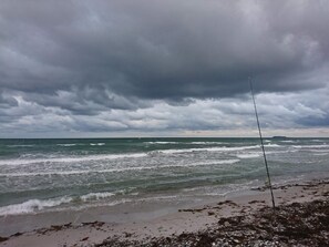 A beach with waves, a fishing rod, and a cloudy sky.