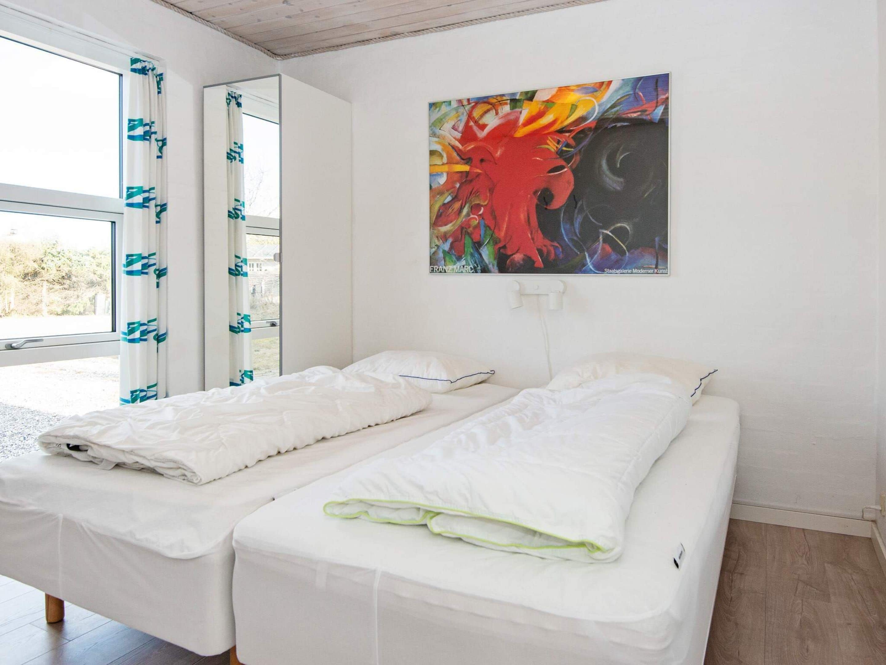 A room with two beds, a window with curtains, and a painting on the wall.