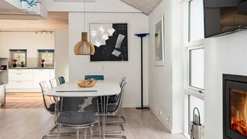 Una cocina moderna con comedor, que cuenta con un amplio ventanal, una chimenea y una obra de arte contemporánea en la pared.