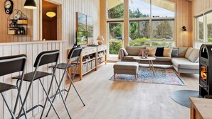 Un salon chaleureux avec des murs en bois, une cheminée, un canapé et un téléviseur.
