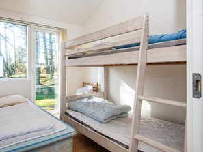 A bunk bed room with a window, a chair, and a mattress on the floor.