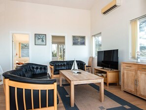 A modern living room with leather sofas, a wooden coffee table, a television, and artwork on the walls.