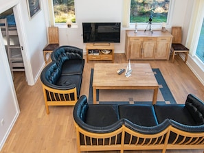 A modern living room with a sofa set, a coffee table, a TV, and a view of the outdoors.