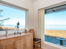 Una habitación con un armario de madera, una silla y un telescopio en el alféizar de una ventana.