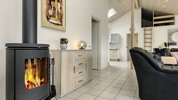 A modern living room with a wood-burning stove, a dining area, and a kitchen.