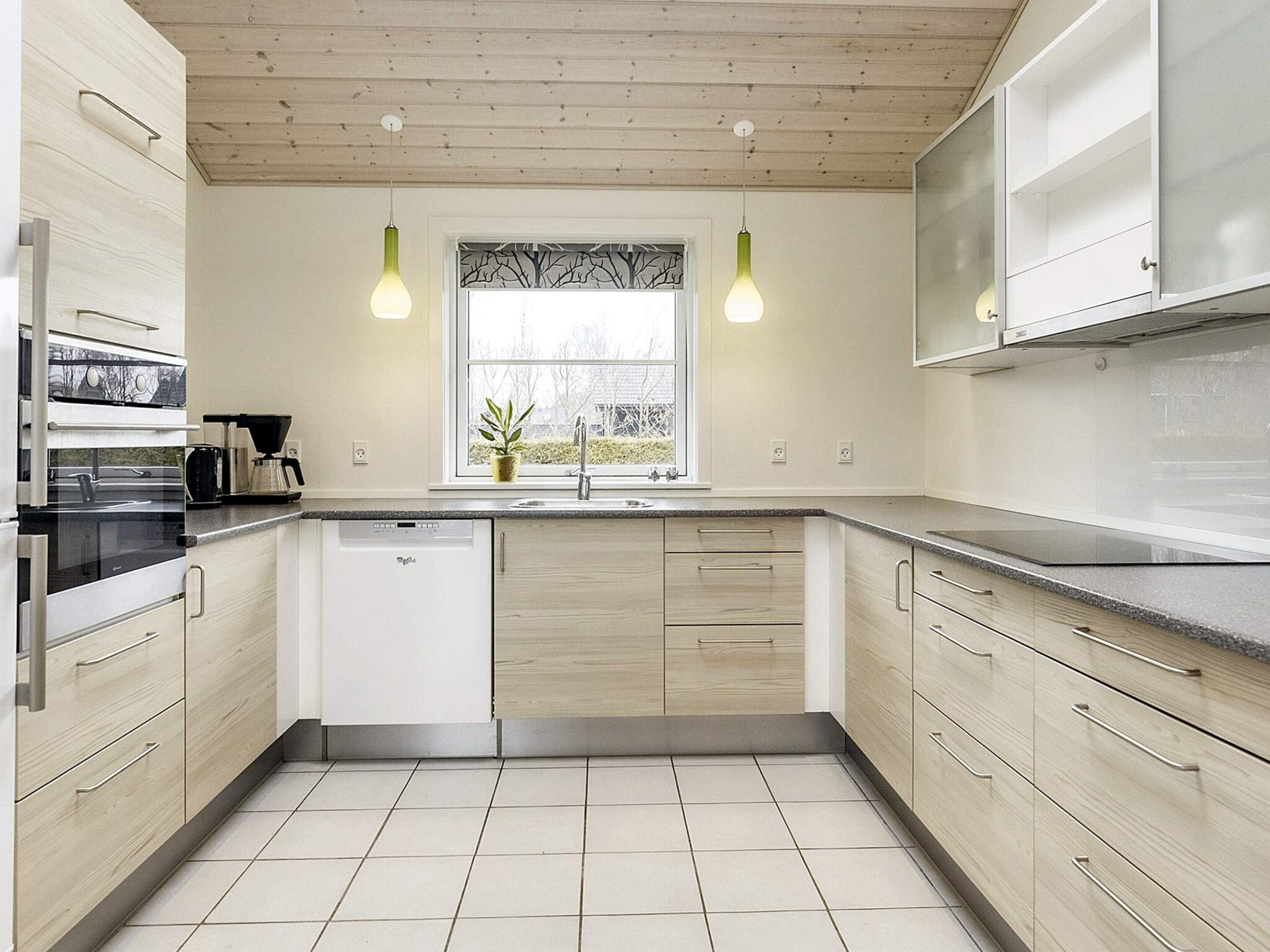 Une cuisine moderne avec des meubles de couleur bois clair, un lave-vaisselle encastré et une fenêtre offrant une belle vue.