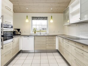 A modern kitchen with light wood cabinets, a built-in dishwasher, and a window with a view. - Roomy Holiday Home in Falster near Sea (Vaeggerlose)