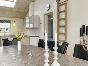 A dining area with a round table, chairs, candles, and a clock on the wall.