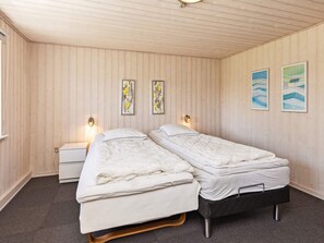 Una habitació amb dos llits, parets de fusta i obra d'art.