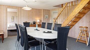 Un comedor con una mesa redonda, sillas negras y una escalera de madera.