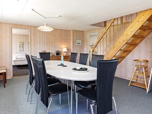 Un coin repas avec une table ronde, des chaises noires et un escalier en bois.