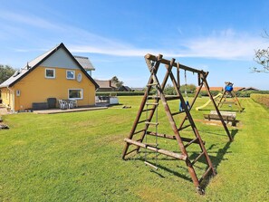 A residential property with a yellow house, a wooden swing set, and a well-maintained lawn. - Spacious Holiday Home in Vinderup near Fjord (Vinderup)