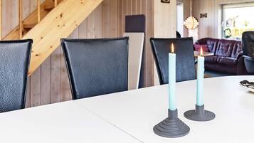 Una mesa de comedor con dos velas, una escalera de madera y un sofá de cuero al fondo.