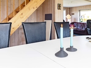 A dining table with two candles, a wooden staircase, and a leather couch in the background. - Spacious Holiday Home in Vinderup near Fjord (Vinderup)