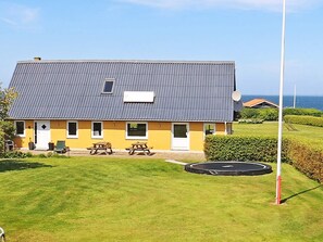 Une maison à deux étages avec un toit gris, un petit balcon et une antenne parabolique.