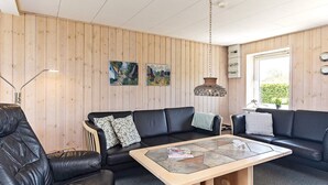 A modern living room with a black leather sofa, a wooden coffee table, and a hanging pendant light. - Spacious Holiday Home in Vinderup near Fjord (Vinderup)